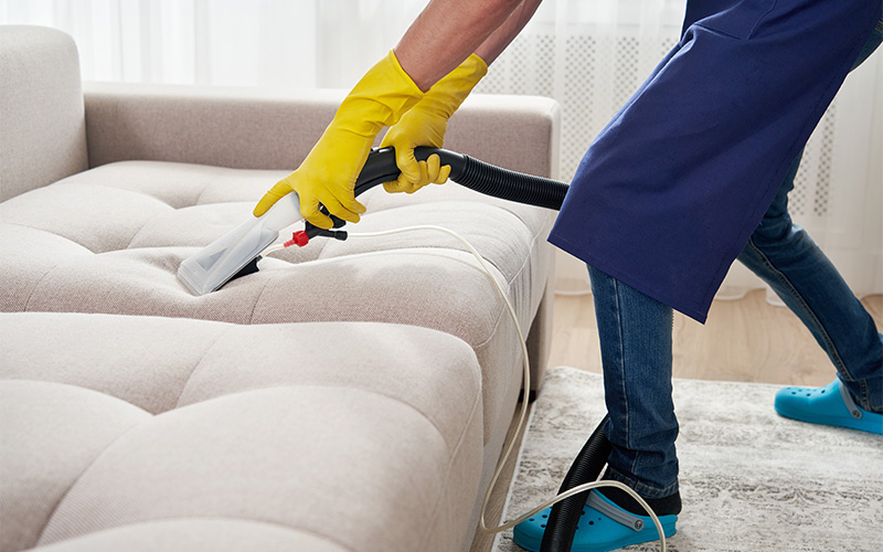 Professional deep cleaning a fabric couch to remove stains.