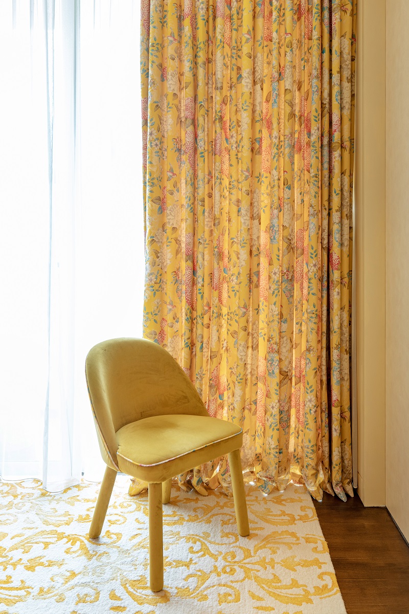 Modern yellow chair paired with vintage patterned floral curtains.